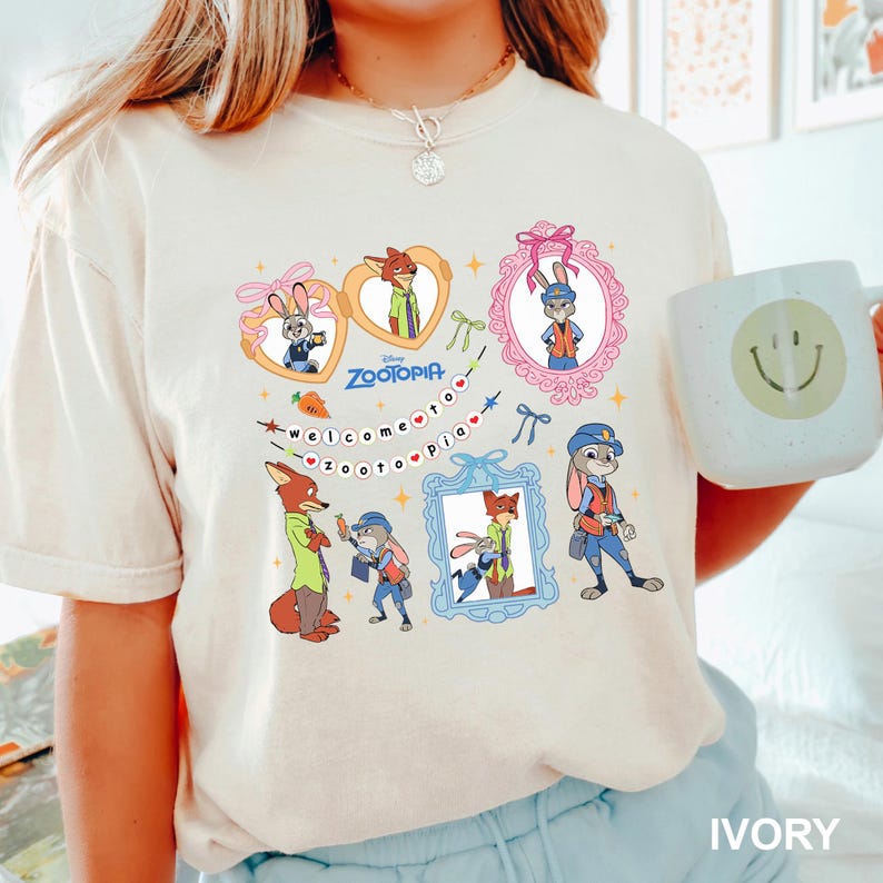 May include: Ivory t-shirt with a colourful cartoon design of Zootopia characters. The design includes framed portraits, hearts, and the text "Welcome to Zootopia". A white mug with a smiley face is also visible in the image.