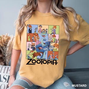 Puede incluir: Camiseta de color mostaza con un gr&aacute;fico colorido de personajes de la pel&iacute;cula animada "Zootopia". El dise&ntilde;o incluye una serpiente, un zorro y un conejo, con la palabra "Zootopia" en letras negras. La camiseta es de estilo casual.