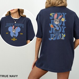May include: True navy blue t-shirt featuring Judy Hopps from Zootopia. The front design includes the text "Judy Hopps" and a cartoon image of Judy. The back of the shirt has a larger image of Judy with the text "Judy" repeated.