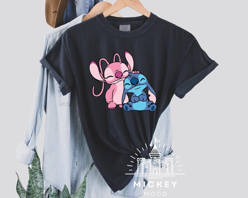 May include: Black t-shirt with a pink and blue cartoon Stitch and Angel design. The text "MICKEY MOOD" is printed below the characters.