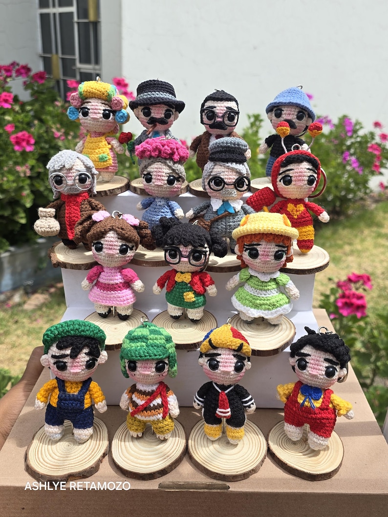 May include: A collection of handmade crochet dolls, each depicting a different character with unique outfits and accessories. The dolls are displayed on small wooden slices, showcasing a variety of colors and designs. The name "ASHLYE RETAMOZO" is visible at the bottom.