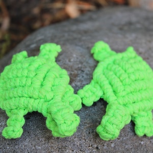 May include: Two bright green crocheted turtle toys. The turtles are made of thick yarn and have a textured surface.