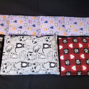 May include: Five different patterned heat packs, including a long rectangular one with a cat pattern, a square one with a paw print pattern, a square one with a cat pattern, a square one with a heart pattern, and a square one with a bone pattern.