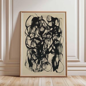 May include: Abstract art print with black ink brushstrokes on a beige background. The print is framed in a light wood frame.