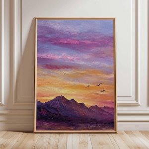 May include: A framed landscape painting shows a sunset over mountains. The sky shifts from pink and purple to orange and yellow. Silhouetted birds fly across the sky. The mountains are a deep purple. The frame is a light brown.