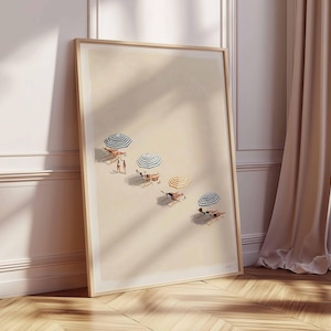May include: A framed art print showing a beach scene with people under striped umbrellas. The artwork has a light colour palette and a wooden frame, leaning against a wall with a curtain and window. The beach umbrellas have blue and white stripes.