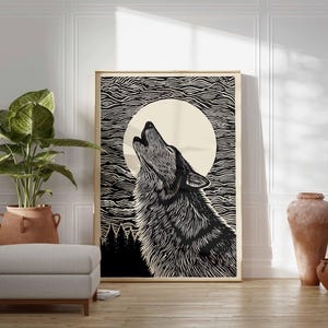 May include: A framed black and white art print shows a howling wolf against a full moon and a textured sky. The artwork is displayed in a room with a large potted plant, a grey ottoman, and decorative pottery.