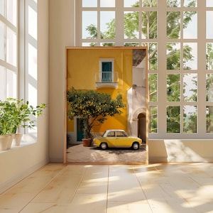 May include: A framed print of a yellow building with a teal balcony and a yellow car parked in front. A tree with yellow fruit is in front of the building. The print is in a room with a window and plants.