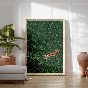 May include: A framed art print featuring a tiger swimming in green water with white wave patterns. The tiger has orange and black stripes. The artwork is in a gold frame and has Japanese text in the lower right corner.