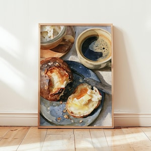 May include: A framed watercolour painting depicting a breakfast scene with a dark blue plate holding a crusty bread roll and a slice of buttered toast. A silver knife rests on the plate next to a ceramic cup of black coffee and a small bowl.
