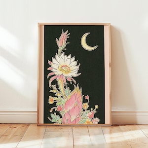 May include: A framed vertical art print featuring a black background with a large white and pink cactus flower in full bloom, smaller pink buds, and yellow and orange floral accents. A yellow crescent moon is positioned in the upper right corner.
