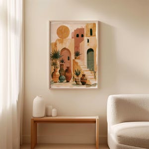 Peut inclure: Une peinture &agrave; l'aquarelle encadr&eacute;e repr&eacute;sente un village m&eacute;diterran&eacute;en ensoleill&eacute;. L'&oelig;uvre pr&eacute;sente des b&acirc;timents aux tons p&ecirc;che et beige, avec un escalier, des portes cintr&eacute;es et des pots en terre cuite. Un grand soleil rond est dans le ciel.