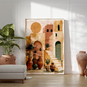 Peut inclure: Une impression d'art abstrait repr&eacute;sentant un village m&eacute;diterran&eacute;en dans des tons chauds de terre. L'&oelig;uvre pr&eacute;sente un grand soleil, des b&acirc;timents, des escaliers et des vases d&eacute;coratifs. Une grande plante en pot et un pouf gris sont au premier plan, avec deux vases en terre cuite &agrave; droite.