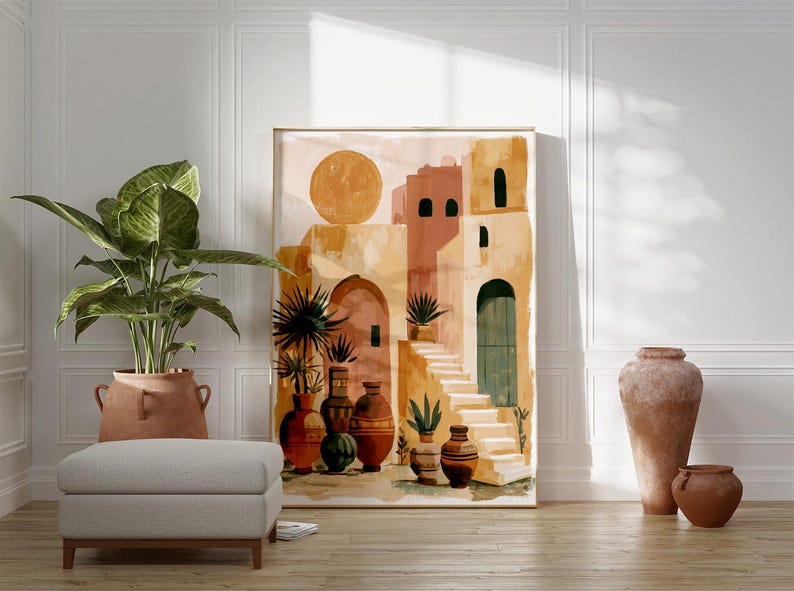 Peut inclure: Une impression d'art abstrait repr&eacute;sentant un village m&eacute;diterran&eacute;en dans des tons chauds de terre. L'&oelig;uvre pr&eacute;sente un grand soleil, des b&acirc;timents, des escaliers et des vases d&eacute;coratifs. Une grande plante en pot et un pouf gris sont au premier plan, avec deux vases en terre cuite &agrave; droite.