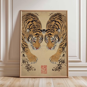 May include: Framed artwork featuring two tigers facing each other. The tigers have orange and black stripes, red eyes, and are set against a beige background. The artwork has a traditional Asian art style with a red seal.