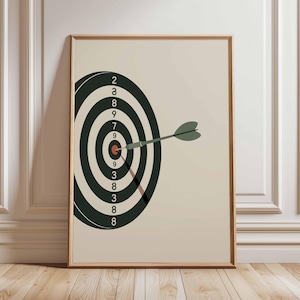 Peut inclure: Impression encadrée d'une cible de fléchettes avec une fléchette atteignant le centre. Le jeu de fléchettes est noir et blanc avec des chiffres. La fléchette est verte. Le fond est beige neutre.