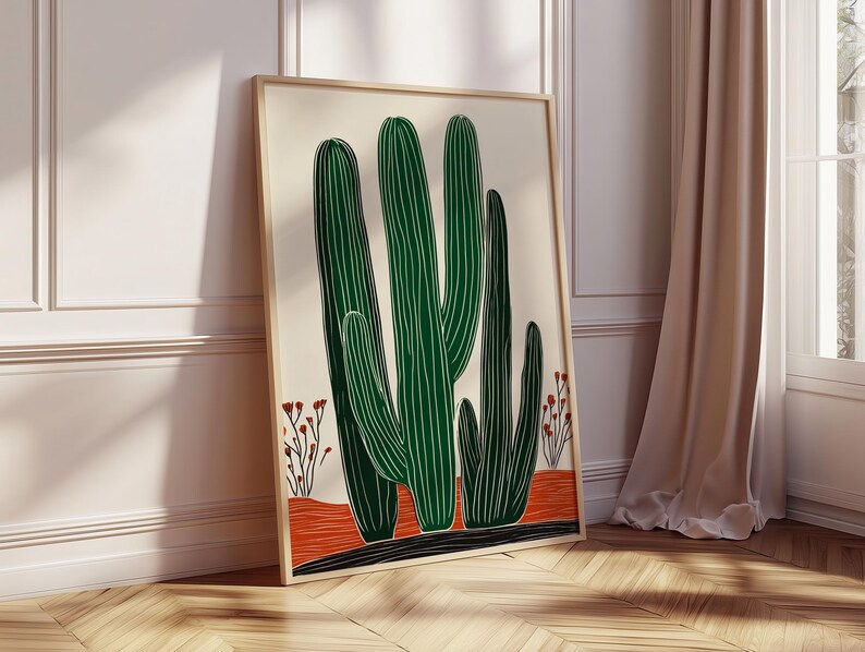 May include: A framed art print featuring a stylized illustration of green cacti with white vertical lines against a cream background. The cacti stand on a red and black base, with small red floral accents. The artwork is displayed in a light wood frame.