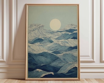 May include: Framed art print depicting stylized ocean waves in shades of blue and white, with a large, pale yellow sun in the sky. The artwork is in a wooden frame and leans against a white wall and wooden floor.