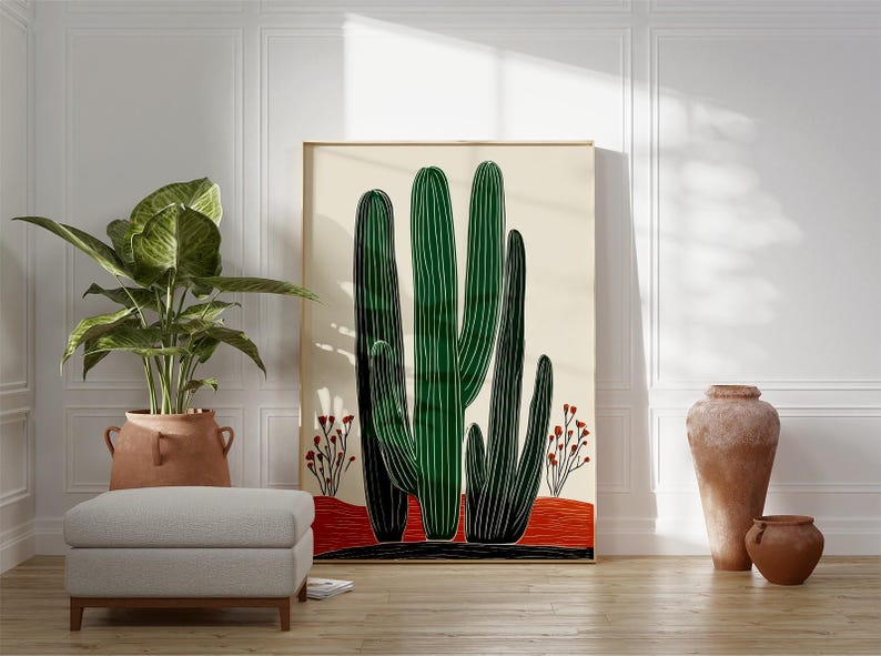 May include: A large framed art print featuring a stylized illustration of green cacti against a cream background. The artwork includes red and black accents, and is displayed in a room with a potted plant, ottoman, and decorative pottery.