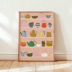 Op de afbeelding: Een ingelijste kunstdruk op een lichtroze achtergrond met vijf horizontale planken gevuld met diverse geïllustreerde theepotten, kommen en kopjes in kleuren zoals mosterdgeel, zwart, wit, roze, oranje, groen en bruin met gestreepte patronen.