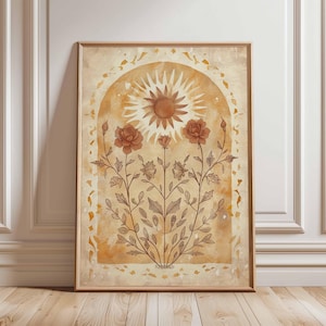 May include: Framed art print with a sunburst design above stylized roses and foliage. The artwork uses warm, earthy tones of brown and beige, with a vintage aesthetic. The print is displayed in a wooden frame.