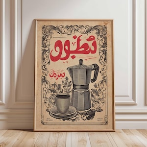 Puede incluir: Impresión artística de café enmarcada de estilo vintage. La impresión presenta una escritura árabe roja en la parte superior, una cafetera, una taza y un platillo, y adornos florales. La paleta de colores incluye tonos rojos, negros y beige.