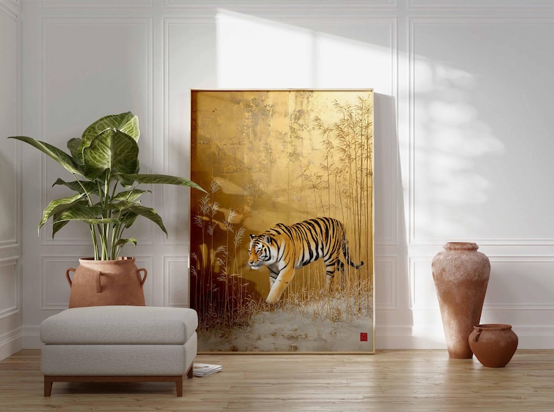 K&ouml;nnte beinhalten: Ein gro&szlig;es gerahmtes Kunstwerk zeigt einen Tiger, der durch einen goldenen Bambuswald geht. Der Tiger hat orange und schwarze Streifen. Das Kunstwerk wird in einem Raum mit einer Pflanze, einem Hocker und dekorativen Vasen ausgestellt.