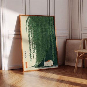 May include: A framed art print featuring a serene scene of a cat resting under a weeping willow tree. The artwork has a traditional Japanese aesthetic, with a color palette of green, cream, and brown. The cat is white with orange markings.