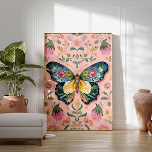 May include: A large framed canvas art piece featuring a colorful butterfly design. The butterfly has blue, yellow, and green wings with floral patterns. The background is a pink floral pattern. The artwork is displayed in a room with a plant and a footstool.