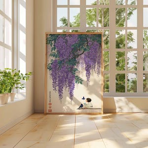 May include: A framed print of a Japanese-style painting featuring purple wisteria blossoms cascading down. A figure sits reading, with a bird and butterfly nearby. The artwork is displayed in a room with a window and plants.