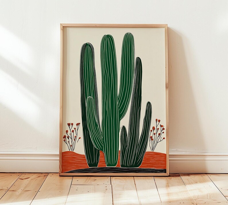 May include: A framed art print featuring a stylized illustration of green cacti with vertical white lines. The cacti are set against a cream background with a red-orange base and small red floral accents. The frame is a light wood color.