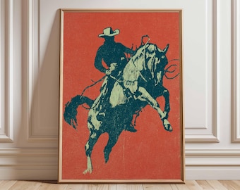 May include: A framed art print featuring a cowboy riding a bucking bronco. The artwork uses a two-tone color scheme of teal and orange, with the cowboy and horse in teal against an orange background. The cowboy wears a hat and is holding the reins.