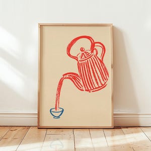 Op de afbeelding: Een ingelijste kunstprint op een lichtbeige achtergrond met een rode, getextureerde, handgetekende illustratie van een gestreepte theepot die vloeistof in een klein, eenvoudig blauw kopje giet. Het kunstwerk heeft een rustieke uitstraling.