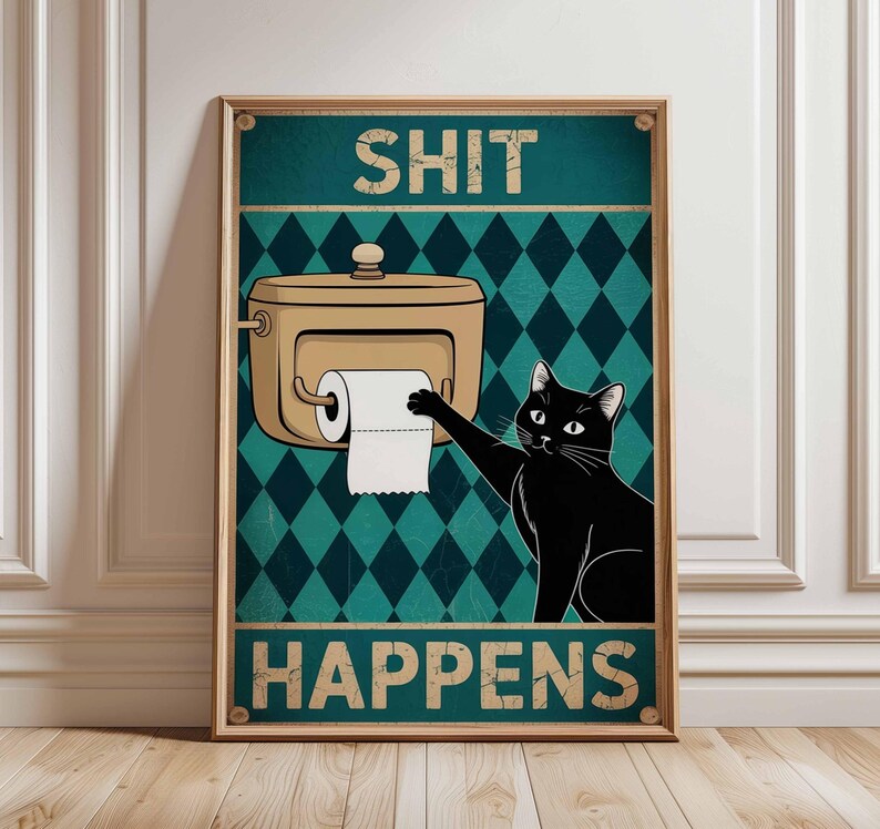 May include: A framed poster with a humorous design. It features a black cat reaching for toilet paper from a dispenser, with the words "SHIT HAPPENS" in bold letters. The background has a teal diamond pattern.