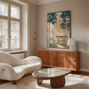 May include: A living room scene featuring a cream-colored, curved sofa, a wooden coffee table with a glass top, and a wooden cabinet. A framed artwork depicting a Japanese landscape with a red torii gate hangs on the wall. A white lamp and a wooden floor lamp are also present.
