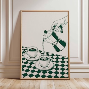 May include: A framed art print depicts a hand pouring coffee from a stovetop espresso maker into a cup. The illustration is in green and white, with a checkered tablecloth and two cups on saucers. The artwork has a vintage aesthetic.