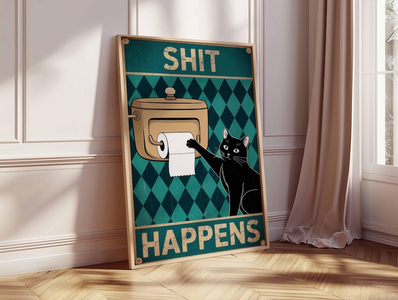 May include: A framed poster with the text "SHIT HAPPENS" and a cartoon image of a black cat reaching for toilet paper. The background is teal with a diamond pattern, and the frame is a light brown color.