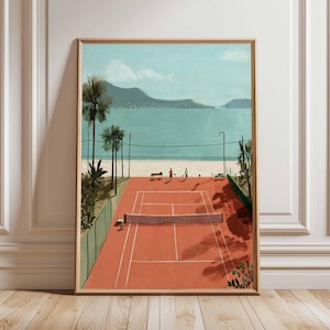 Puede incluir: Una impresión artística enmarcada representa una escena de cancha de tenis. La cancha es de color rojo anaranjado, con una red y jugadores. El fondo presenta un mar turquesa, montañas y palmeras. La obra de arte está en un marco de madera.