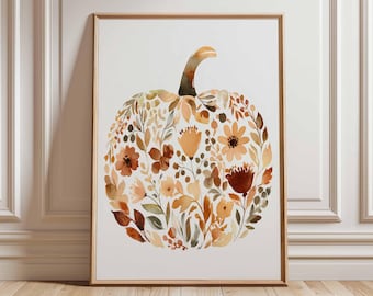 May include: A framed watercolor print featuring a pumpkin shape composed of autumn-toned flowers and foliage. The artwork showcases shades of orange, brown, and yellow, with a light background and a wooden frame.