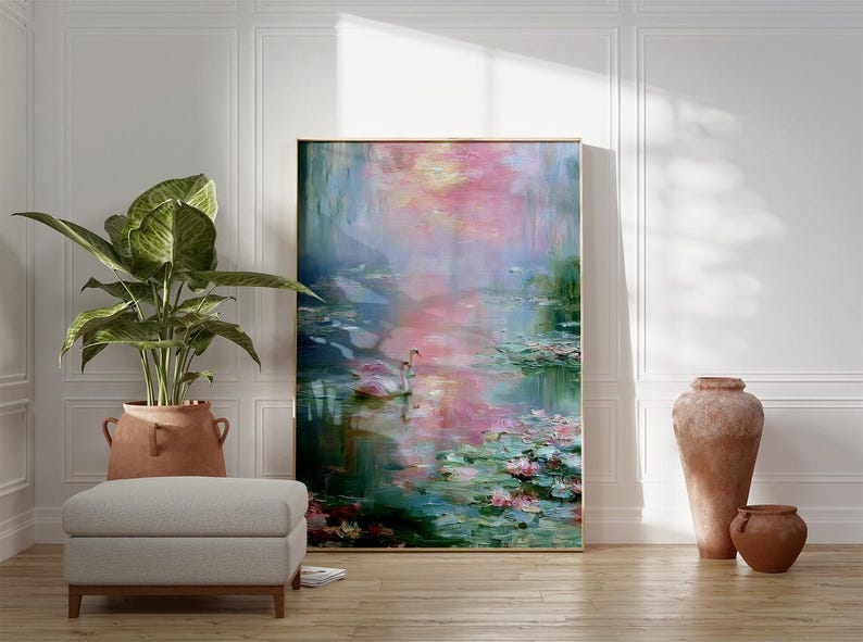 May include: An abstract painting of a water scene with pink and blue hues, framed in gold. A pair of swans floats on the water, surrounded by lily pads. A large potted plant and a gray ottoman are in the foreground.