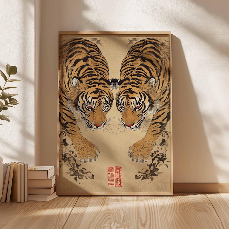 May include: Framed art print featuring two tigers facing each other. The tigers have orange and black stripes, red eyes, and are set against a beige background. The artwork is in a wooden frame and has Japanese text.