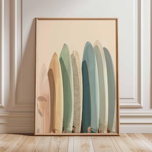 Op de afbeelding: Een ingelijste print met een rij surfplanken in zachte pastelkleuren, waaronder roze, geel, groen en blauw. De surfplanken staan verticaal tegen een neutrale achtergrond, wat een kust- of strandthema oproept.