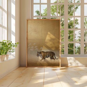 May include: A framed art print featuring a tiger walking across a field. The artwork has a gold background with a tiger in shades of orange, black, and white. The print is displayed in a room with a large window and hardwood floors.
