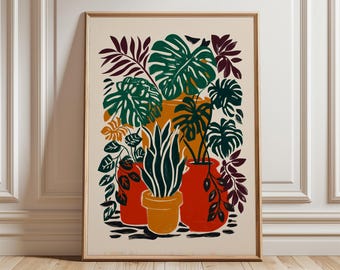 May include: A framed art print featuring a vibrant illustration of potted plants. The artwork showcases green monstera leaves, tall white and green plants, and other foliage in orange and red pots against a cream background. The frame is a light brown color.