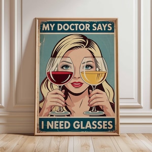 May include: A framed vintage-style poster with the text "MY DOCTOR SAYS I NEED GLASSES." The image features a woman holding a glass of red wine and a glass of white wine in front of her eyes. The poster has a distressed, aged look.