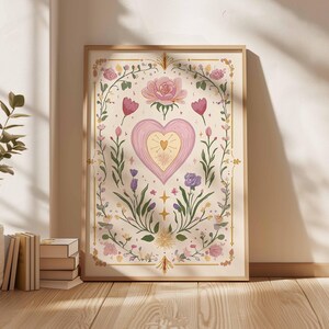May include: A framed art print featuring a central pink heart design with a golden center, surrounded by floral and botanical elements. The artwork includes roses, tulips, and other flowers in soft pastel colors, framed in a light wood. The overall theme is romantic and whimsical.