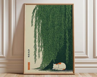 May include: A framed print featuring a sleeping cat under a weeping willow tree. The cat is white with orange markings. The tree has green leaves. The print has Japanese text and is in a wooden frame.