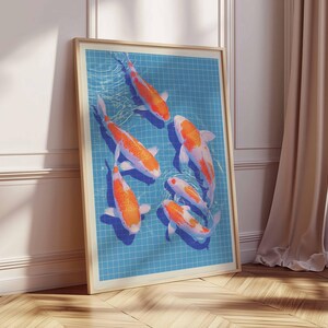 May include: A framed print showing six koi carp in a blue tiled pool. The fish are orange and white. The artwork is displayed on a wooden floor, leaning against a white wall. The frame is light brown.