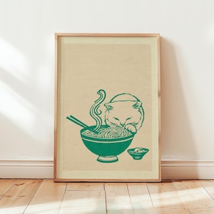 May include: A framed vertical art print on a light beige background featuring a dark green line drawing of a cat eating noodles from a bowl with chopsticks. A small side bowl is positioned to the right of the main bowl, completing the illustration.