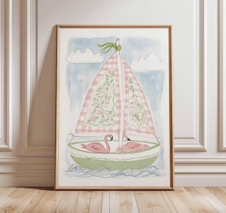 May include: Watercolor painting of a sailboat with pink and white checkered sails and floral details. Two pink flamingos are in the boat. The boat is green with blue water and a light blue sky with white clouds. The artwork is framed in a wooden frame.